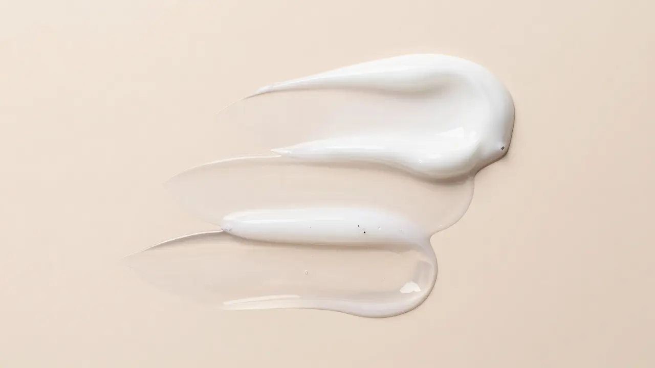 Makro detail vrstvení kosmetiky od lehkého séra po hustý pleťový krém.